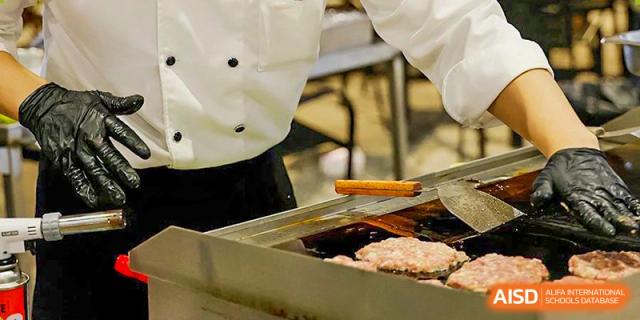 A close-up of burger patties cooking on a flat-top grill in the school kitchen at Shenzhen International Foundation College (SIFC).