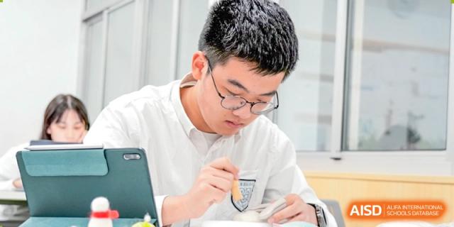 A male student from Suzhou Innovation Academy focused on writing or an assignment during a class.