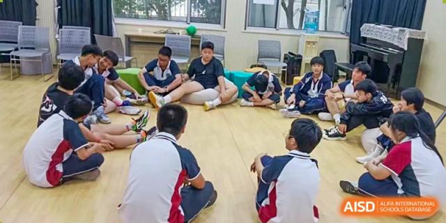 Suzhou Innovation Academy students participating in a group discussion while seated in a circle on the floor in a relaxed classroom setting.