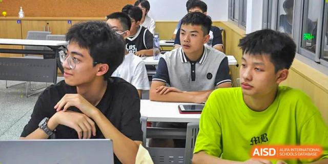 A close-up of male students at Suzhou Innovation Academy actively listening to a lecture or presentation in a classroom.