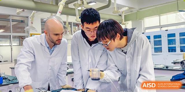 Two male students and a teacher in lab coats working on a science experiment or practical task in a lab at Suzhou Innovation Academy.