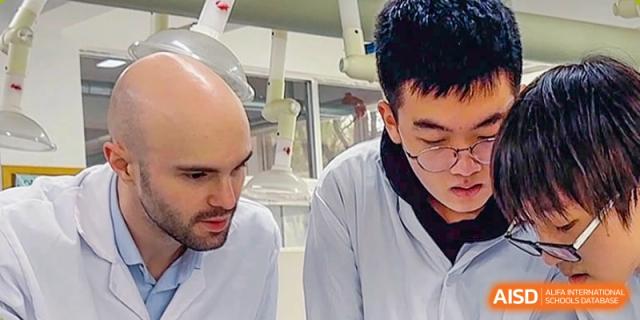 A close-up of a male student and a teacher in lab coats performing a detailed procedure in a science lab at Suzhou Innovation Academy.