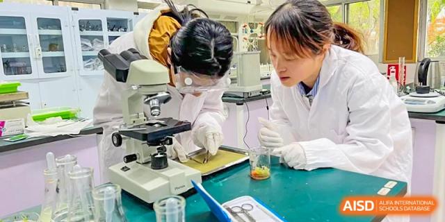 A student in safety goggles and a lab coat working with a microscope during a science class at Suzhou Innovation Academy.
