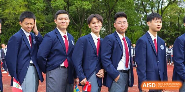 Three male students from Suzhou Innovation Academy in navy blue blazers, white shirts, and red ties posing for a portrait outdoors.