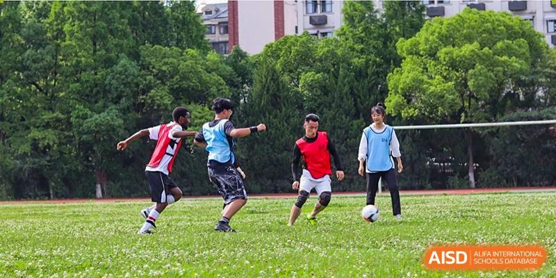 Suzhou Innovation Academy students playing soccer or football intensely on a green grass field outdoors.