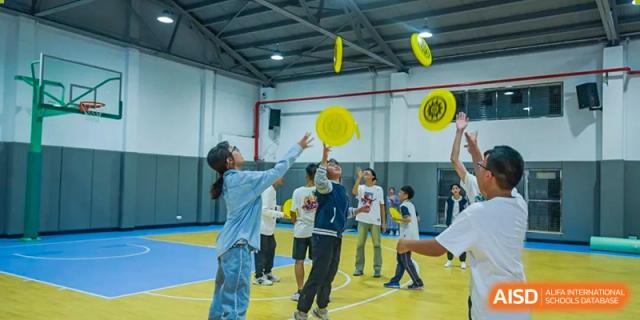 Suzhou Innovation Academy students playing a game of frisbee or flying disc indoors in a gymnasium.