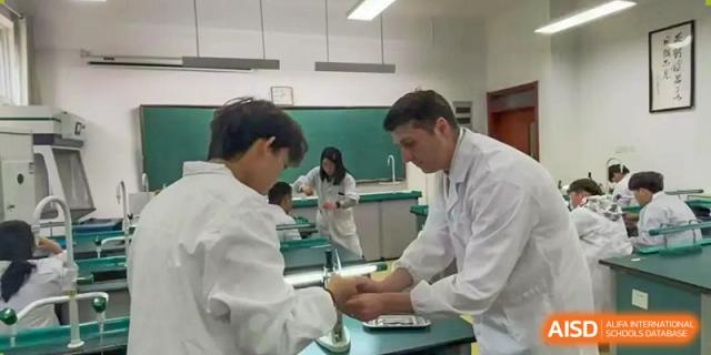 A teacher assisting a student with a hands-on activity or experiment in a science lab at Walton International School Xuzhou.