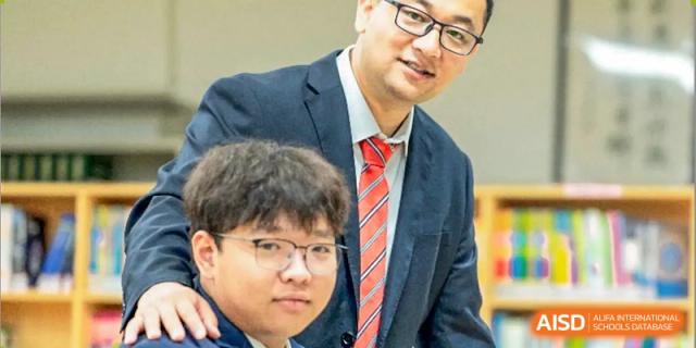 A close-up portrait of a male teacher in a tie and glasses, with a student next to him, representing the faculty of Walton International School Xuzhou.