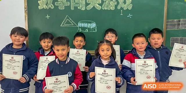 A group of happy young students at Walton International School Xuzhou proudly holding certificates in front of a classroom chalkboard.