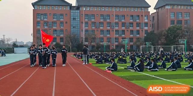 Students walking on the red running track with the main school building of Walton International School Xuzhou in the background.