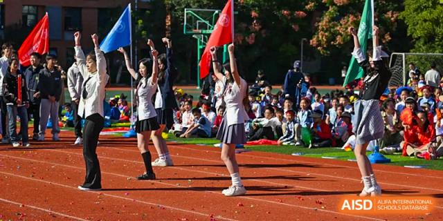 A cheerleader in uniform performing a stance on the track during a sports day event at Walton International School Xuzhou.