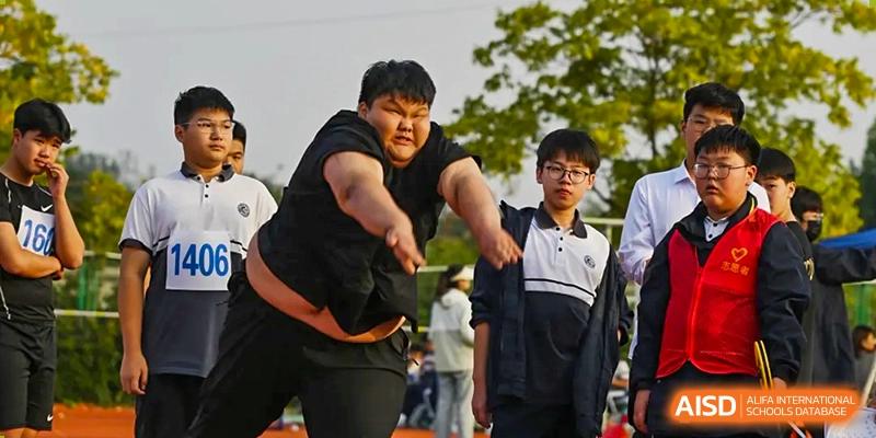 A student participating in a throwing event, possibly shot put or discus, on the sports field at Walton International School Xuzhou.
