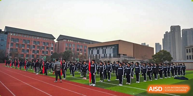 Students in uniform lined up for a formation or assembly in front of the main building of Walton International School Xuzhou.