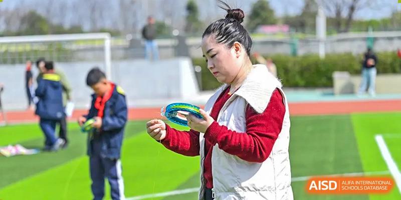 A female student preparing to throw a discus or ring on the green turf at Walton International School Xuzhou.