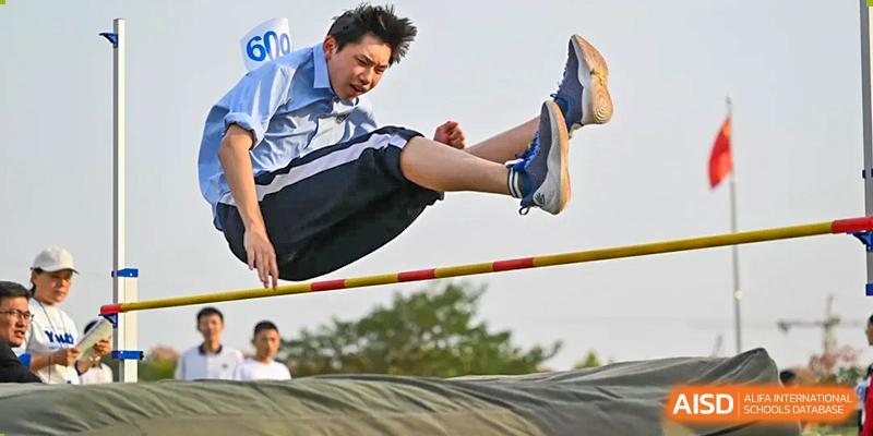 A male student performing the high jump over the bar at a sports event at Walton International School Xuzhou.