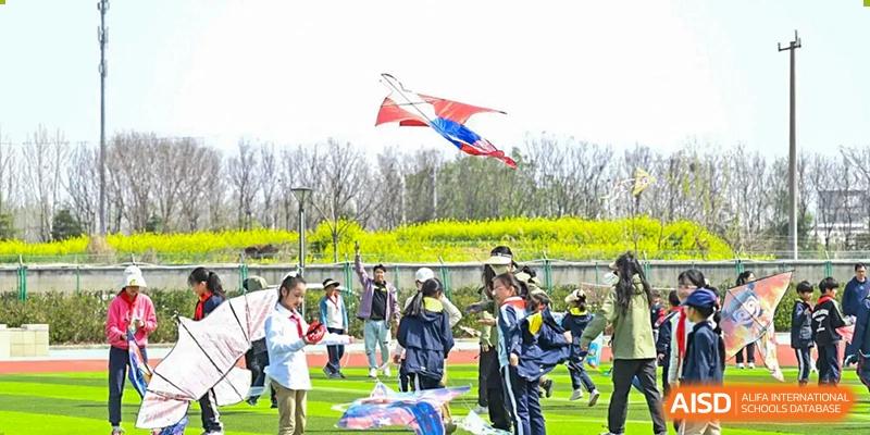 Students gathered on the field with flags flying in the background during an outdoor event at Walton International School Xuzhou.