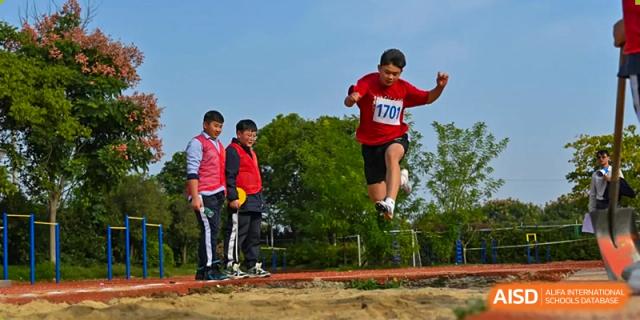 A student performing the long jump or triple jump onto the sand pit during an athletic competition at Walton International School Xuzhou.