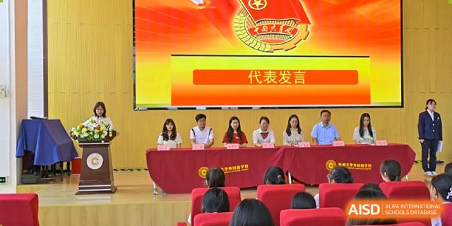 A group of students or faculty seated at a table during a formal presentation or speech event at Walton International School Xuzhou.