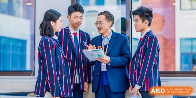 Two individuals, one in a striped uniform, shaking hands and smiling at Wuxi Huatian Bilingual School.