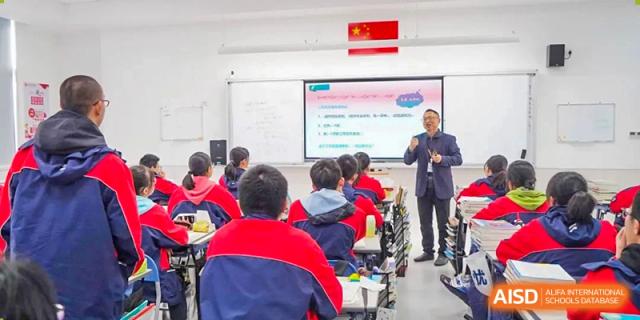 Students in red and blue uniforms learning in a modern classroom at Wuxi Huatian Bilingual School.
