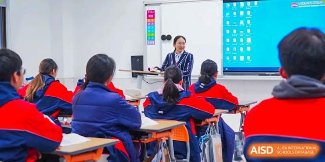 A teacher walking amongst students seated at desks in a classroom at Wuxi Huatian Bilingual School.