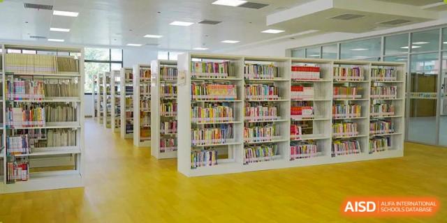 Well-lit school library interior with rows of books and shelves at Wuxi Huatian Bilingual School.