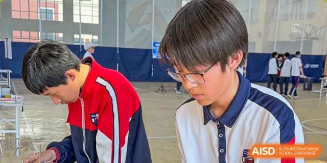 A male student wearing glasses, concentrated on a task or reading at Wuxi Huatian Bilingual School.