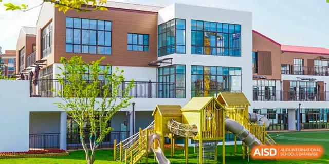 Wuxi Huatian Bilingual School kindergarten or primary section building exterior with large windows and a bright yellow outdoor playground set.