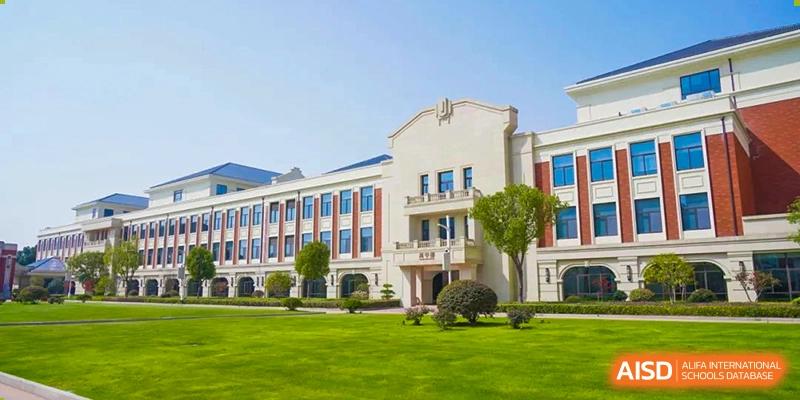 Main administrative or academic building of Wuxi Huatian Bilingual School with a light-colored facade, manicured lawn, and a classical architectural style.