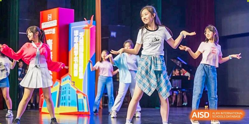 Wuxi Huatian Bilingual School student performing a lively dance routine on stage in front of an audience.