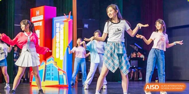 Wuxi Huatian Bilingual School student performing a lively dance routine on stage in front of an audience.
