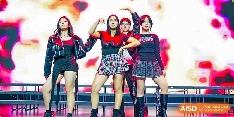 Wuxi Huatian Bilingual School students in plaid and black outfits performing a dynamic group dance.
