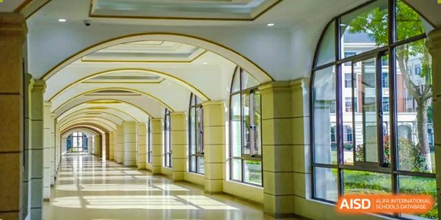 A bright, expansive hallway with arched windows inside Wuxi Huatian Bilingual School campus building.