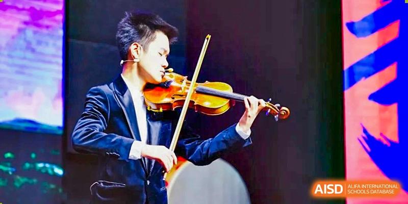 A student from Wuxi Huatian Bilingual School focused on playing the violin during a musical performance.