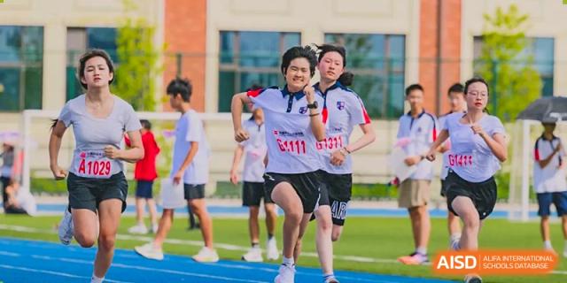 Wuxi Huatian Bilingual School students running on a blue track during a sports day competition.