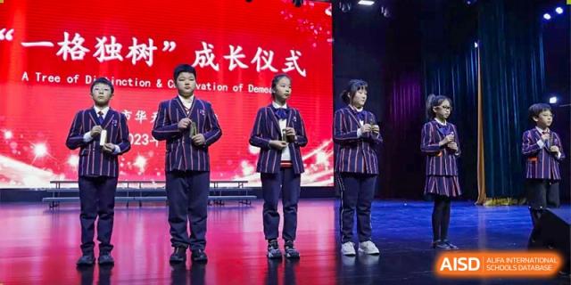 Wuxi Huatian Bilingual School students and staff on stage during a graduation or declaration ceremony.