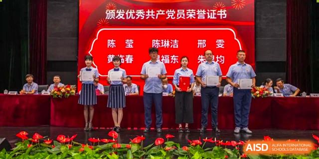 Group of staff and administrators from Wuxi Huatian Bilingual School on stage for a ceremony, holding awards or certificates.