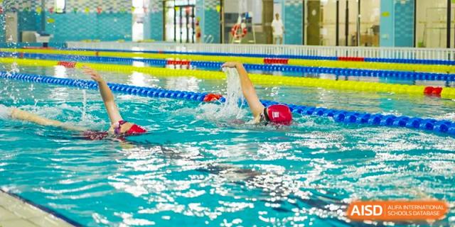 Wuxi Huatian Bilingual School student swimming the butterfly stroke competitively in the school's indoor swimming pool.