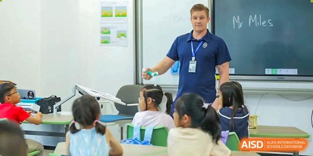 A male teacher at Wycombe Abbey School Hangzhou giving a presentation to a group of young students in a bright classroom.
