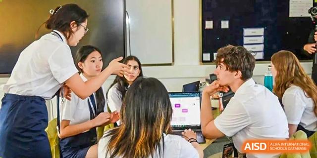 A group of Wycombe Abbey School Hangzhou students gathered around a laptop in a classroom.