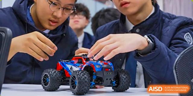 Wycombe Abbey School Hangzhou students gathered around and working with a remote-controlled toy truck in a hands-on activity.