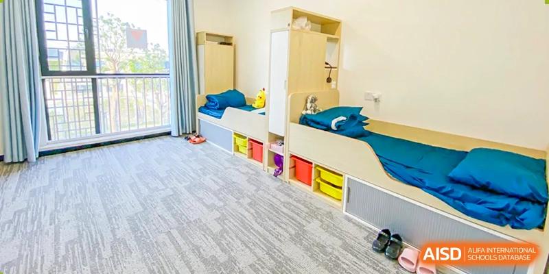 Interior of a student dormitory room with two beds, built-in storage, and bright rugs at Wycombe Abbey School Hangzhou.