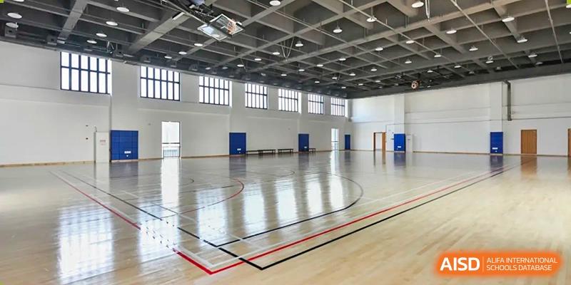 Interior of the spacious gymnasium or sports hall with a polished wooden floor and court lines at Wycombe Abbey School Hangzhou.