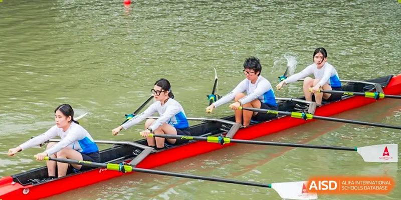 Two students in uniform practicing rowing in a sleek red boat on the water as part of a sports activity at Wycombe Abbey School Hangzhou.