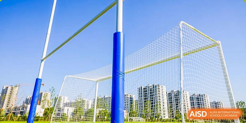 Outdoor volleyball court with a blue pole and netting at Wycombe Abbey School Hangzhou, with city buildings in the background.