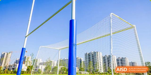 Outdoor volleyball court with a blue pole and netting at Wycombe Abbey School Hangzhou, with city buildings in the background.