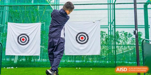 Student or instructor practicing golf swing toward a target on a green at Wycombe Abbey School Hangzhou.