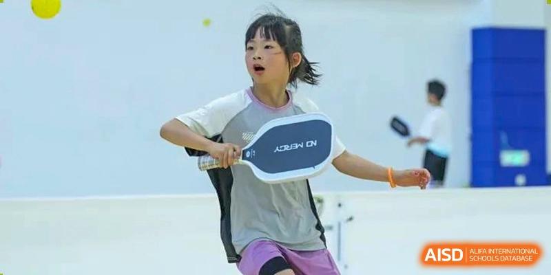 Young female student actively playing table tennis or a similar racket sport at Wycombe Abbey School Hangzhou.