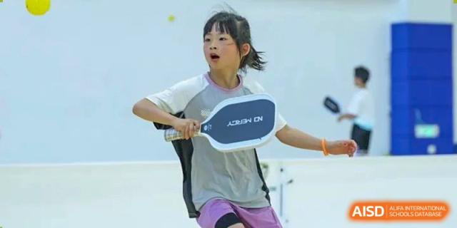 Young female student actively playing table tennis or a similar racket sport at Wycombe Abbey School Hangzhou.