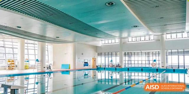 Interior view of a large, brightly lit indoor swimming pool facility with multiple lanes at Wycombe Abbey School Hangzhou.